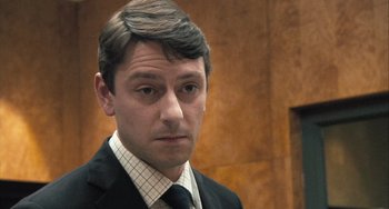 Movie still from “In the Loop” (2009), directed by Armando Iannucci – A person wearing a suit and tie; Close Up shot, Over the shoulder angle