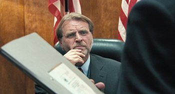 Movie still from “In the Loop” (2009), directed by Armando Iannucci – A man in a suit and tie looking at his reflection in a mirror; Close Up shot, Over the shoulder angle