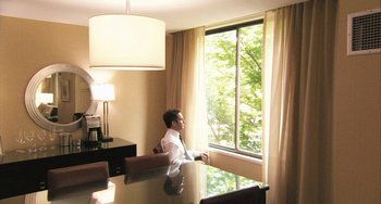 Movie still from “In the Loop” (2009), directed by Armando Iannucci – A man sitting at a table looking out of a window; Wide shot, High angle
