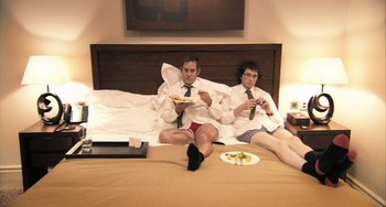Movie still from “In the Loop” (2009), directed by Armando Iannucci – A couple of men sitting on top of a bed; Medium shot, High angle