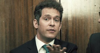 Movie still from “In the Loop” (2009), directed by Armando Iannucci – A person wearing a suit and tie; Close Up shot, Over the shoulder angle