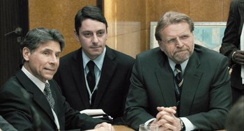Movie still from “In the Loop” (2009), directed by Armando Iannucci – A group of men in suits sitting at a table; Medium shot, Over the shoulder angle