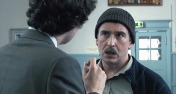 Movie still from “In the Loop” (2009), directed by Armando Iannucci – A man with a mustache is looking in the mirror; Close Up shot, Over the shoulder angle