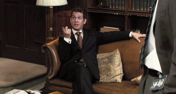 Movie still from “In the Loop” (2009), directed by Armando Iannucci – A man sitting on a couch in a room; Medium shot, High angle