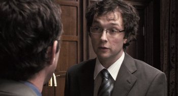 Movie still from “In the Loop” (2009), directed by Armando Iannucci – A man in a suit and tie talking to another man in a suit and tie; Close Up shot, Over the shoulder angle