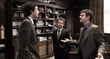 Movie still from “In the Loop” (2009), directed by Armando Iannucci – A group of three men in suits in a room; Medium shot, Over the shoulder angle
