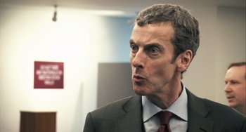 Movie still from “In the Loop” (2009), directed by Armando Iannucci – A person wearing a suit and tie; Close Up shot, Over the shoulder angle