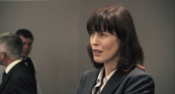 Movie still from “In the Loop” (2009), directed by Armando Iannucci – A woman in a business suit is sitting in a chair; Close Up shot, Over the shoulder angle