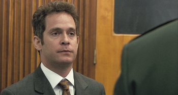 Movie still from “In the Loop” (2009), directed by Armando Iannucci – A person wearing a suit and tie; Close Up shot, Over the shoulder angle