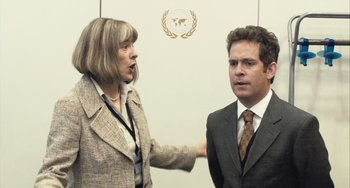 Movie still from “In the Loop” (2009), directed by Armando Iannucci – A woman and a man in business suits talking; Medium shot, Over the shoulder angle