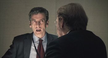 Movie still from “In the Loop” (2009), directed by Armando Iannucci – A man wearing a suit and tie looking at himself in a mirror; Close Up shot, Over the shoulder angle