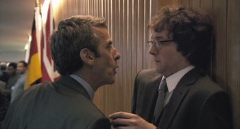 Movie still from “In the Loop” (2009), directed by Armando Iannucci – Two men in business suits talking to each other; Medium shot, Over the shoulder angle