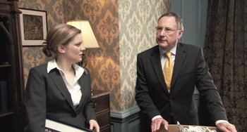 Movie still from “In the Loop” (2009), directed by Armando Iannucci – A man and a woman in business suits; Medium shot, Over the shoulder angle