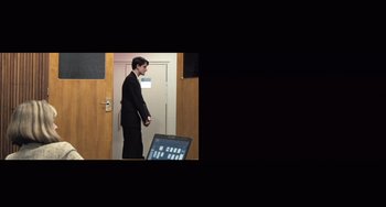 Movie still from “In the Loop” (2009), directed by Armando Iannucci – A man standing in front of an open door; Wide shot, High angle