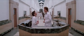 Movie still from “In the Mouth of Madness” (1994), directed by John Carpenter – A couple of people that are talking to each other; Wide shot, Low angle