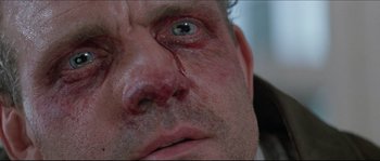 Movie still from “In the Mouth of Madness” (1994), directed by John Carpenter – A person's face with blood on his face; Extreme Close Up shot, Low angle