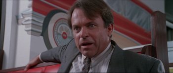 Movie still from “In the Mouth of Madness” (1994), directed by John Carpenter – A person wearing a suit and tie; Close Up shot, Low angle