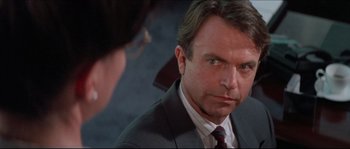 Movie still from “In the Mouth of Madness” (1994), directed by John Carpenter – A man wearing a suit and tie looking into a mirror; Close Up shot, Over the shoulder angle