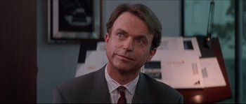 Movie still from “In the Mouth of Madness” (1994), directed by John Carpenter – A person wearing a suit and tie; Close Up shot, Over the shoulder angle