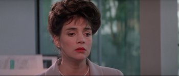 Movie still from “In the Mouth of Madness” (1994), directed by John Carpenter – A person wearing a suit and tie; Close Up shot, Over the shoulder angle