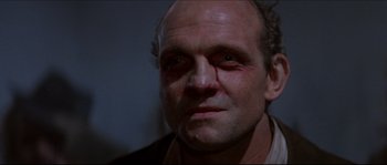 Movie still from “In the Mouth of Madness” (1994), directed by John Carpenter – A person with a bruise on his face; Close Up shot, Low angle