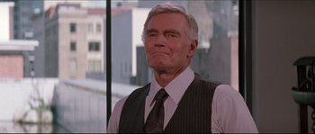 Movie still from “In the Mouth of Madness” (1994), directed by John Carpenter – An older man wearing a vest and a tie; Close Up shot, Low angle