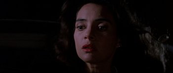 Movie still from “In the Mouth of Madness” (1994), directed by John Carpenter – A person wearing a necklace; Close Up shot, Low angle