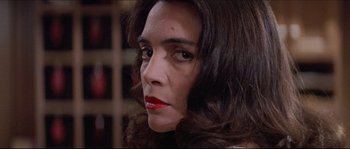 Movie still from “In the Mouth of Madness” (1994), directed by John Carpenter – A person with long dark hair; Close Up shot, Over the shoulder angle