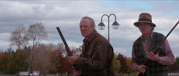 Movie still from “In the Mouth of Madness” (1994), directed by John Carpenter – A man holding a rifle in his hands; Medium shot, Low angle