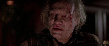 Movie still from “In the Mouth of Madness” (1994), directed by John Carpenter – A person with blood on his face; Close Up shot, Low angle