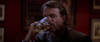 Movie still from “In the Mouth of Madness” (1994), directed by John Carpenter – A man drinking a glass of beer in a bar; Close Up shot, Low angle