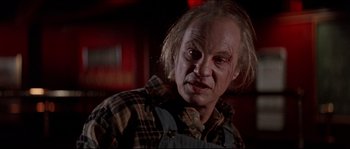 Movie still from “In the Mouth of Madness” (1994), directed by John Carpenter – An old man with a creepy look on his face; Close Up shot, Low angle