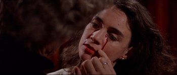 Movie still from “In the Mouth of Madness” (1994), directed by John Carpenter – A woman with blood on her face is holding a knife in her hand; Close Up shot, High angle