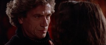 Movie still from “In the Mouth of Madness” (1994), directed by John Carpenter – A person wearing a scarf; Close Up shot, Over the shoulder angle