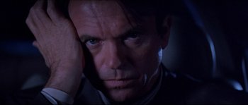 Movie still from “In the Mouth of Madness” (1994), directed by John Carpenter – A person with his hand on his face; Close Up shot, Low angle