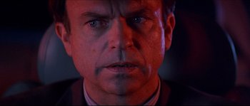 Movie still from “In the Mouth of Madness” (1994), directed by John Carpenter – A man's face in red light; Close Up shot, Low angle