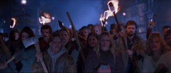 Movie still from “In the Mouth of Madness” (1994), directed by John Carpenter – A group of people holding torches in the dark; Medium shot, High angle