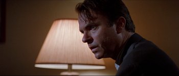Movie still from “In the Mouth of Madness” (1994), directed by John Carpenter – A man's face in front of a lamp; Close Up shot, Low angle