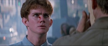 Movie still from “In the Mouth of Madness” (1994), directed by John Carpenter – A young man with a bandage on his face; Close Up shot, Low angle