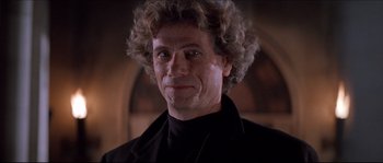 Movie still from “In the Mouth of Madness” (1994), directed by John Carpenter – A person wearing a suit and tie; Close Up shot, Low angle