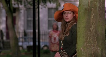 Movie still from “In the Name of the Father” (1993), directed by Jim Sheridan – A woman wearing an orange hat standing next to a tree; Medium shot, Low angle