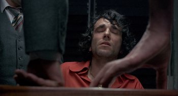 Movie still from “In the Name of the Father” (1993), directed by Jim Sheridan – A man with curly hair is sitting at a table; Close Up shot, Low angle