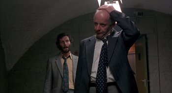 Movie still from “In the Name of the Father” (1993), directed by Jim Sheridan – A man in a suit and tie next to another man in a suit and tie; Medium shot, Low angle