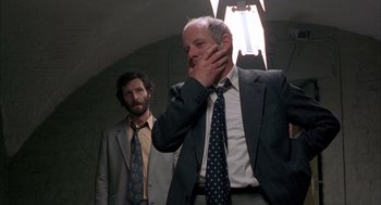 Movie still from “In the Name of the Father” (1993), directed by Jim Sheridan – A man in a suit and tie next to another man in a suit and tie; Medium shot, Low angle