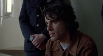 Movie still from “In the Name of the Father” (1993), directed by Jim Sheridan – A man sitting next to another man holding a cell phone; Close Up shot, Low angle