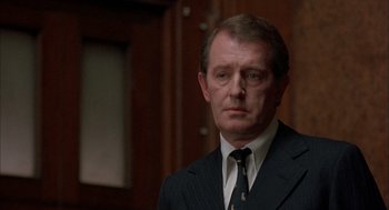 Movie still from “In the Name of the Father” (1993), directed by Jim Sheridan – A person wearing a suit and tie; Close Up shot, Over the shoulder angle