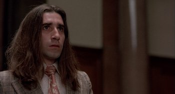 Movie still from “In the Name of the Father” (1993), directed by Jim Sheridan – A man with long brown hair wearing a suit and tie; Close Up shot, Low angle