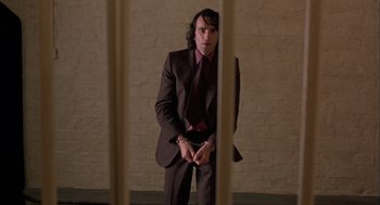 Movie still from “In the Name of the Father” (1993), directed by Jim Sheridan – A man in a suit and tie standing in front of a jail cell; Medium shot, Low angle