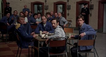 Movie still from “In the Name of the Father” (1993), directed by Jim Sheridan – A group of men sitting at a table with coffee cups; Wide shot, High angle