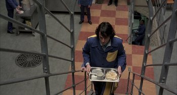 Movie still from “In the Name of the Father” (1993), directed by Jim Sheridan – A man carrying a tray of food down a flight of stairs; Medium shot, Overhead angle